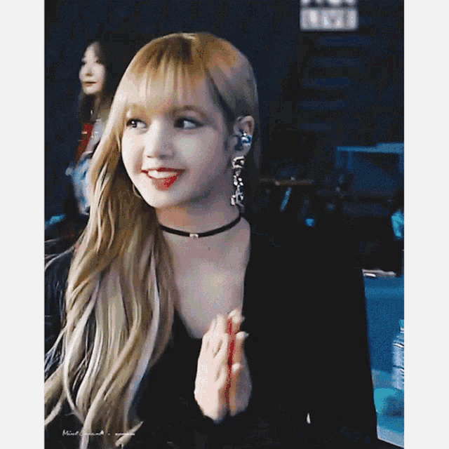 a woman wearing a choker and earrings is smiling and clapping her hands