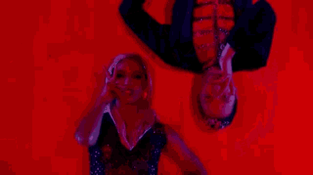 a man and a woman are hanging upside down in a red room .
