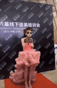 a woman in a pink dress is standing in front of a wall that says sanman