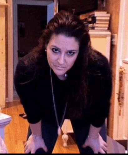 a woman wearing a black shirt and a necklace is kneeling down on the floor