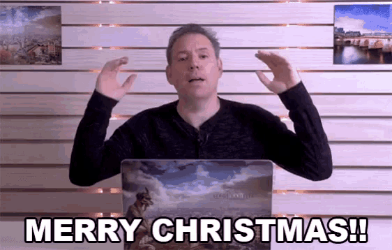 a man in front of a laptop says merry christmas !