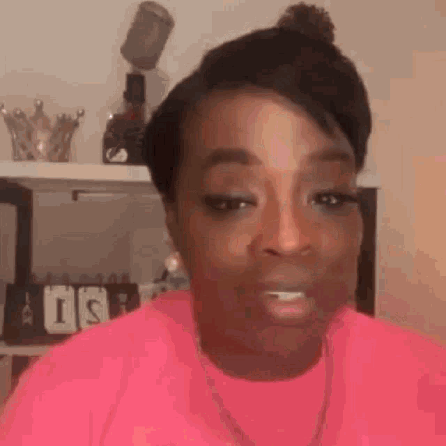 a woman in a pink shirt is looking at the camera .
