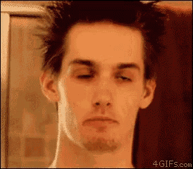 a man with his eyes closed looks at himself in the mirror .