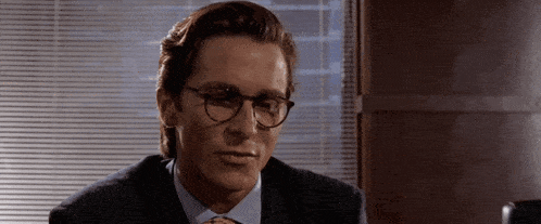 a man wearing glasses and a suit looks to the side