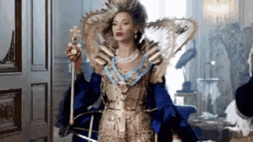 a woman in a queen costume is holding a crown and a sword .