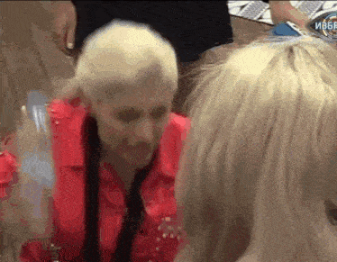 a woman in a red jacket is standing next to another woman