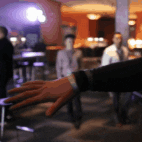a blurry picture of a person 's hand reaching out in a restaurant