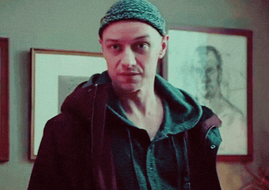a man wearing a beanie and a jacket is standing in front of a framed picture