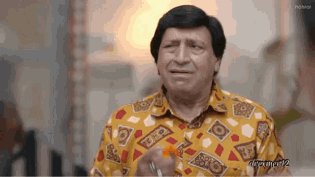 a man in a yellow shirt with a pattern on it is holding something in his hand