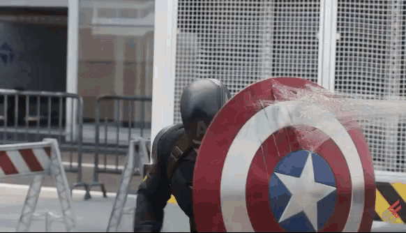 a man in a black suit is holding a captain america shield