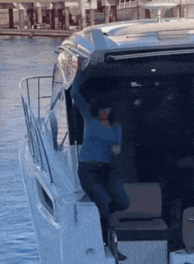 a woman in a blue sweater is standing on a boat in the water