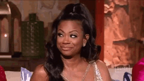 a woman in a dress is sitting on a couch and making a face .