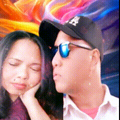 a man wearing a ny hat and sunglasses stands next to a woman with her eyes closed
