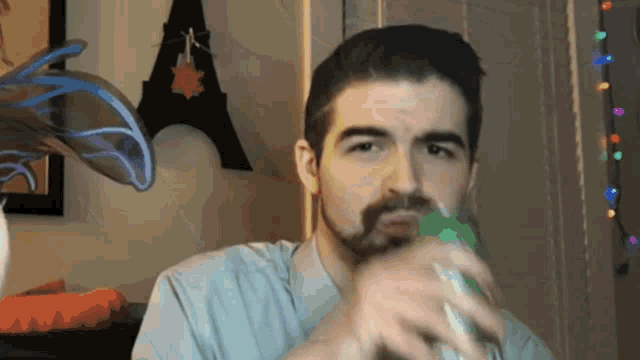 a man with a beard is drinking from a green bottle in front of an eiffel tower
