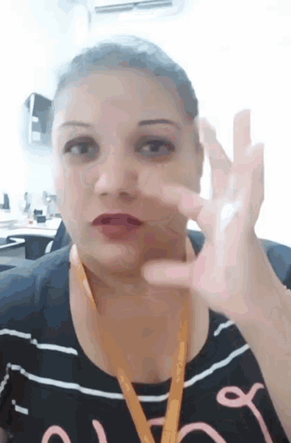a woman with a lanyard around her neck is making a gesture with her hand