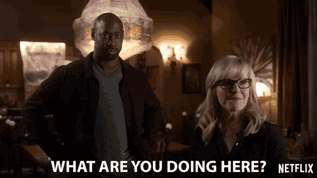 a man and a woman are standing in a dark room with the words what are you doing here netflix written on the bottom