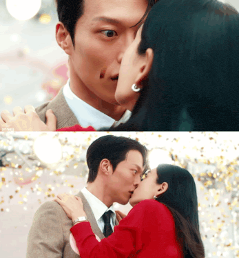 a man in a suit and tie kisses a woman in a red jacket
