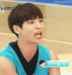 a young man in a blue tank top is making a face