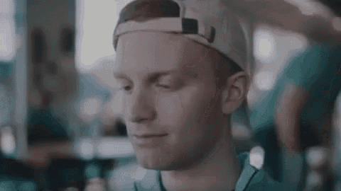a young man wearing a baseball cap is smiling and looking at his phone .