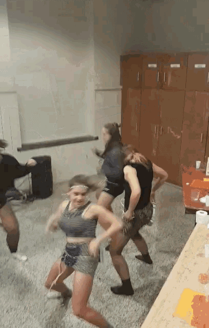 a group of girls are dancing in a room with boxes on the wall that say ' a '