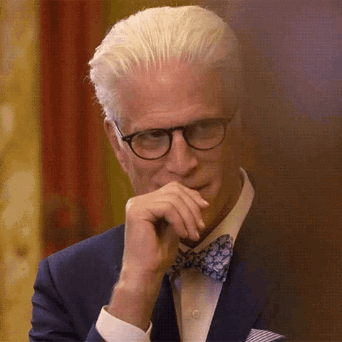 a man in a suit and bow tie is holding his hand to his chin .