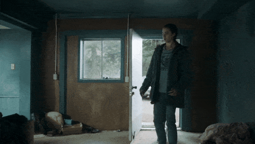 a man in a superman shirt stands in a room