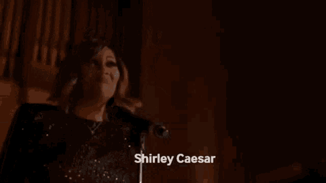 a woman is singing into a microphone in a dark room and saying `` ain 't retired '' .
