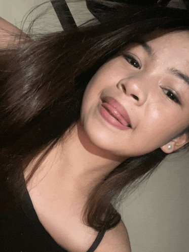 a girl with her tongue out and a black tank top on