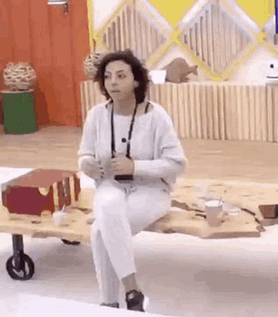 a woman in white pants is sitting on a wooden table .