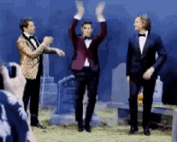 three men in tuxedos and bow ties are dancing in a cemetery .