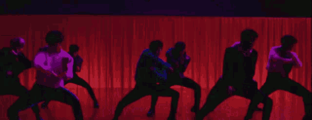a group of young men are dancing in front of a stage