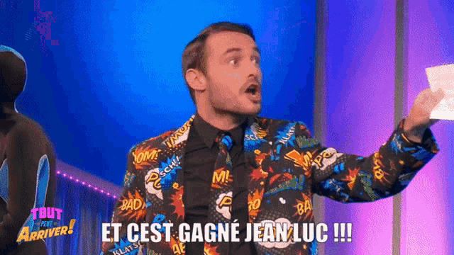 a man in a suit and tie is holding a piece of paper and says " et cest gagne jean luc !!! "