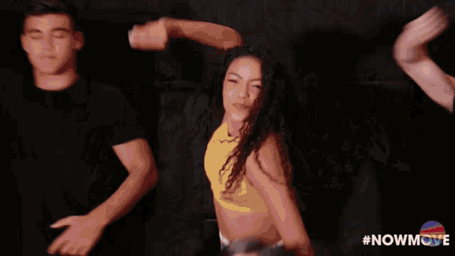 a woman in a yellow crop top and black pants is dancing in front of a nowmove logo