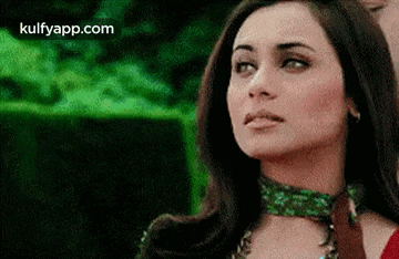 a close up of a woman 's face with a green background and the words kulfyapp.com on the bottom .