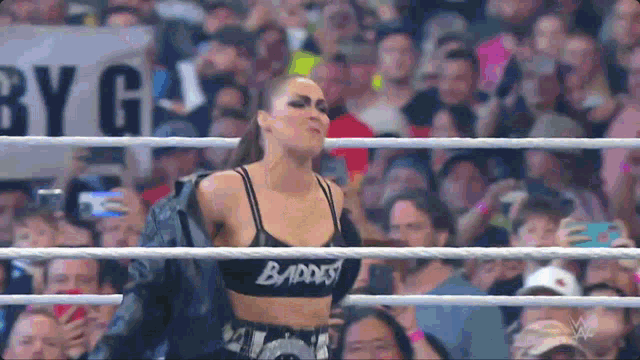 a woman is standing in the middle of a wrestling ring .