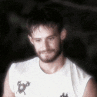 a blurry picture of a man with a beard wearing a white t-shirt