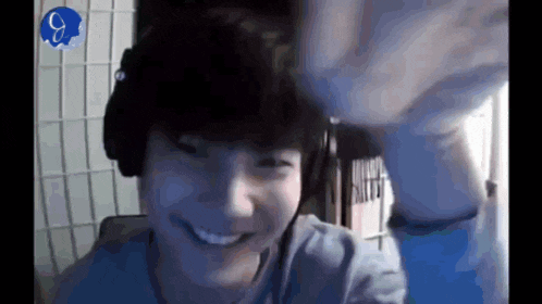 a man wearing headphones is smiling and waving his hand .