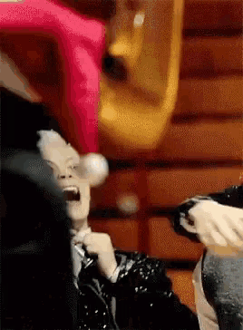 a man in a black jacket is holding a microphone and screaming while another man looks on .