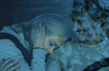 a man and woman are sleeping in a car