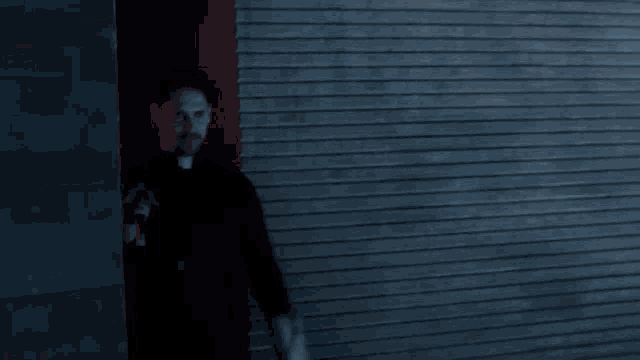 a man in a black shirt stands in front of a brick wall