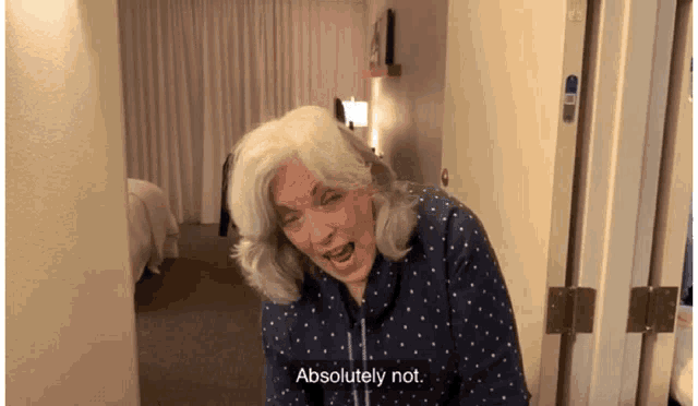a woman in a blue and white polka dot shirt is saying absolutely not