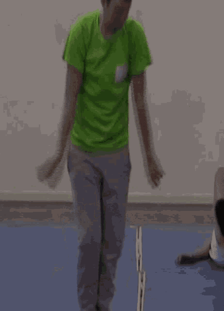 a man in a green shirt is kneeling on a blue mat .