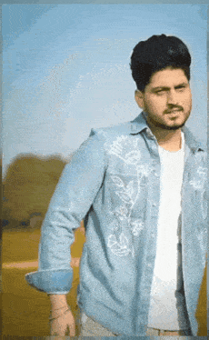 a young man wearing a blue denim shirt with white flowers on it