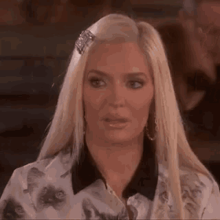 a woman with blonde hair is wearing a white shirt with cats on it .