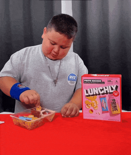 a young boy is eating a box of lunchily cereal