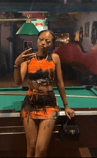 a woman takes a selfie in front of a pool table