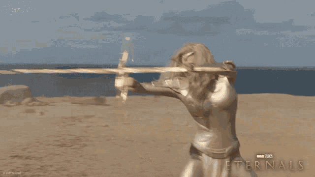 a poster for the movie eternals shows a blonde woman holding a golden object