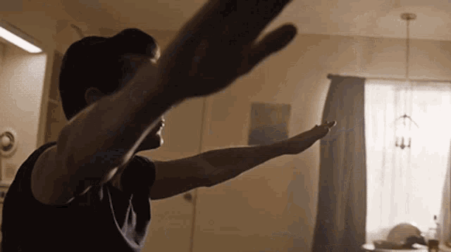 a man in a black shirt is stretching his arms out in a living room
