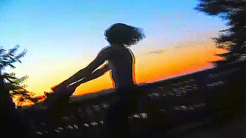 a person is standing on top of a hill with their arms outstretched .