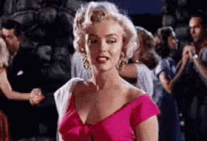 a woman in a pink dress is standing in front of a group of people dancing .